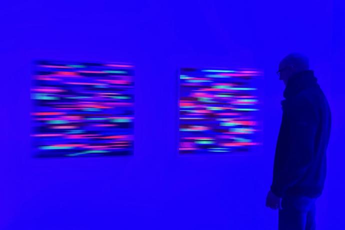 Christiane Grimm, Verschmelzungen XI und X, 2023, Mischtechnik und Acrylglas, je 80 x 80 x 10 cm, im Schwarzlicht, Ausstellungsansicht Galerie Corona Unger, Bremen, mit Betrachter